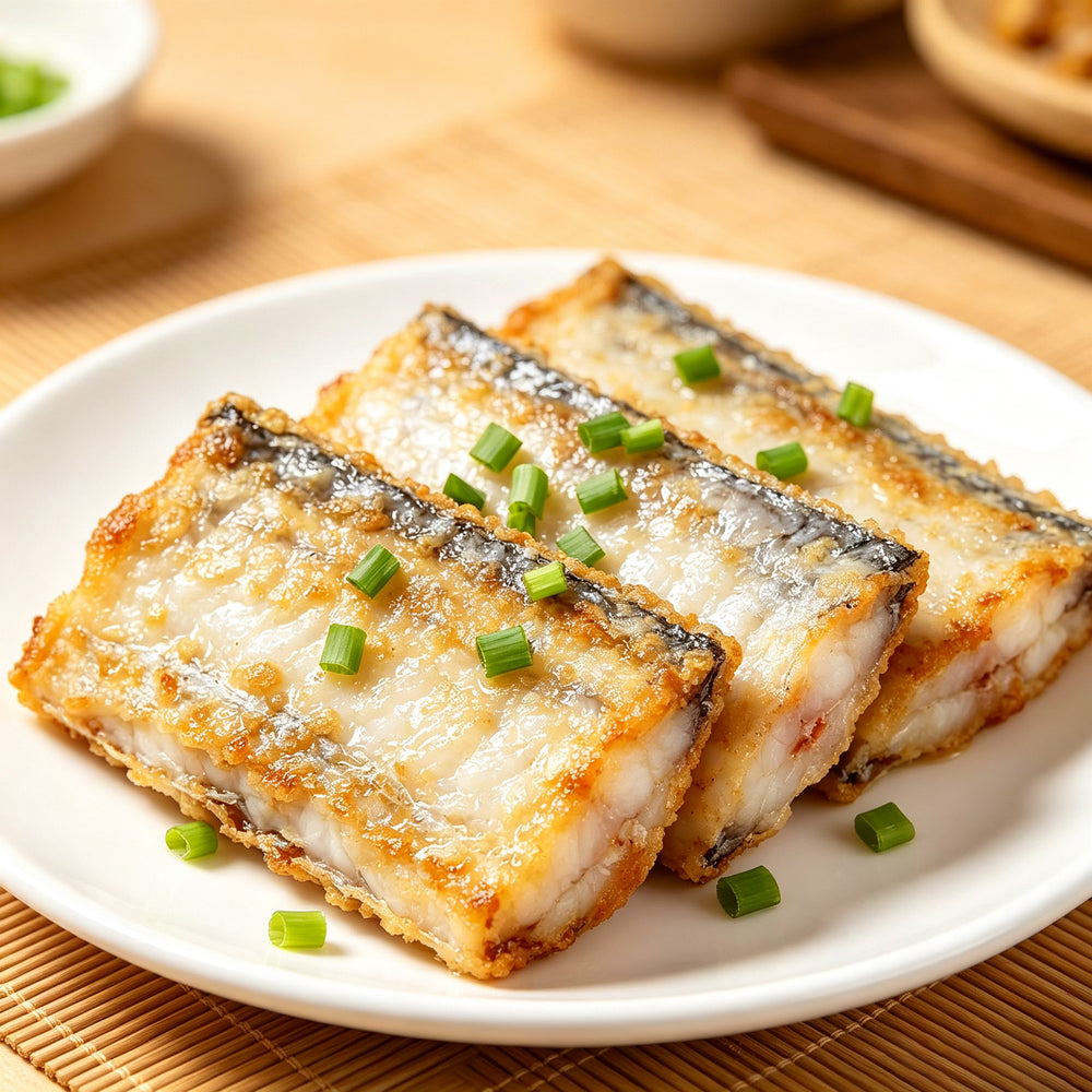 Golden pan-fried beltfish sections on a white plate with scallion