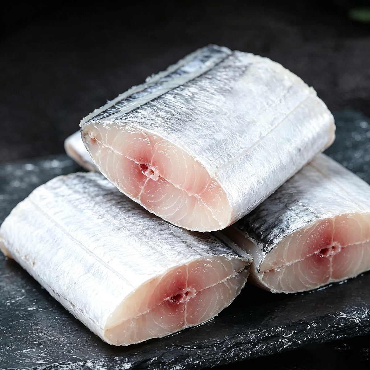 Close-up of raw beltfish steaks showing silvery skin and white flesh