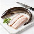 Raw eel fillets next to a whole eel on a white board